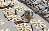 Nahaufnahme eines OCS-Federsystems mit quadratischen Kunststofftellern und einer Stahlkugel, die zur Veranschaulichung der Druckverteilung auf dem System liegt.